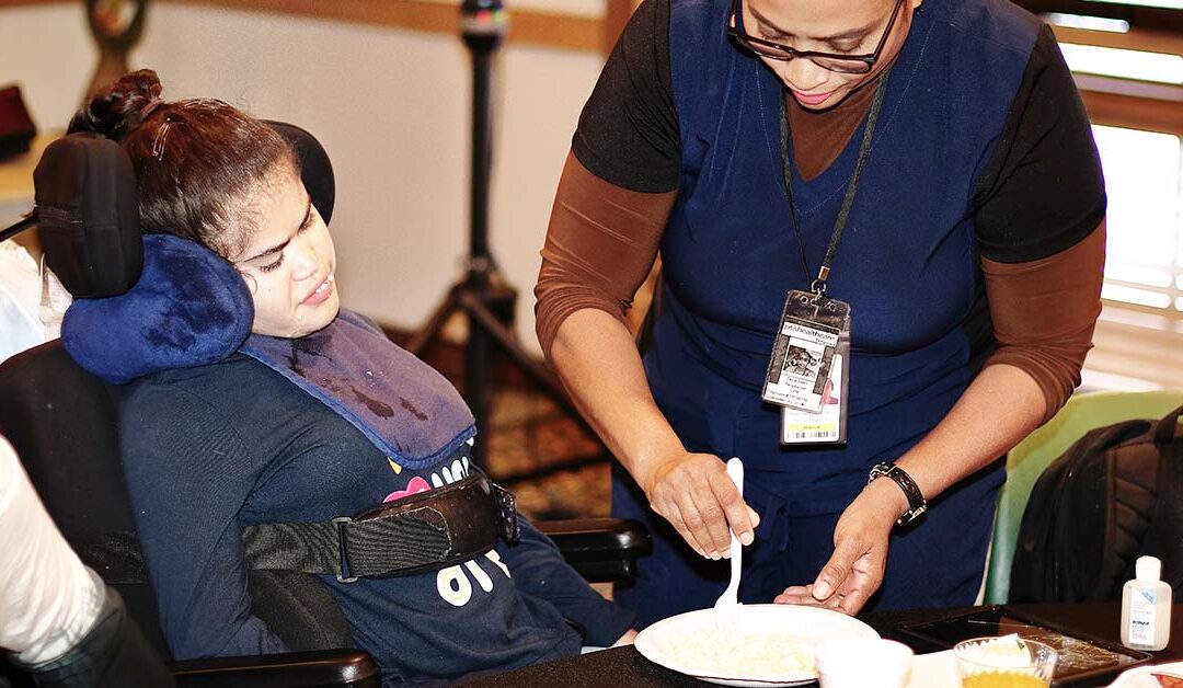 Ragazza disabile viene imboccata da un'infermiera